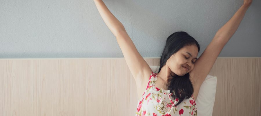 Mujer estirándose con energía en la cama aplicando la técnica de respiración de 1 minuto de Primero Salud.